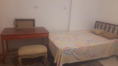 um quarto com uma cama ao lado de uma secretária e uma roupa de cama. em مزرعة الدكتور محمد رجب em Alexandria