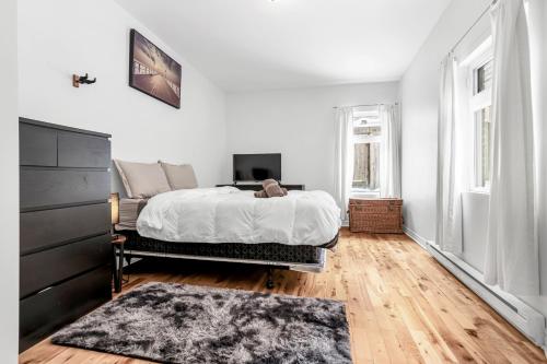 a white bedroom with a bed and a rug at DUPLEX FOR GROUP STAY_MONT-ROYAL in Montréal