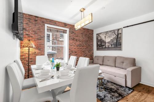 a dining room with a brick wall and a white table and chairs at DUPLEX FOR GROUP STAY_MONT-ROYAL in Montréal