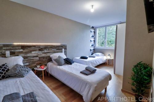 a room with three beds and a window at Appart hotel Cholet Carteron in Cholet