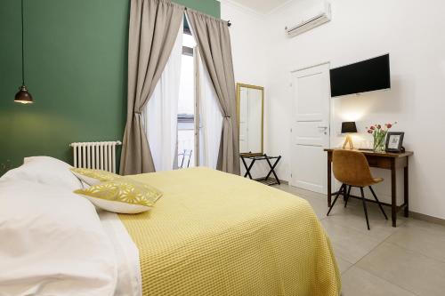 1 dormitorio con 1 cama con manta amarilla y escritorio en Crianza B&B, en Nápoles