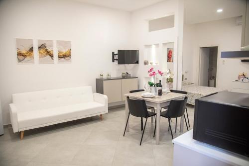 een woonkamer met een witte bank en een tafel bij Dimora Asmara 11 15 in Brindisi