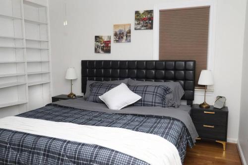 a bedroom with a large bed with a black headboard at Charming, Central, Cozy Home - Ideal in Dearborn Heights