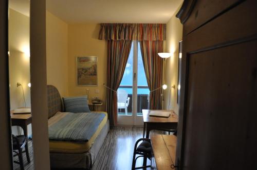 a hotel room with a bed and a desk and a window at Seehotel Bären in Brienz