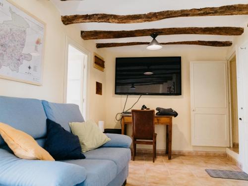 a living room with a blue couch and a desk at La Maysou in Masroig