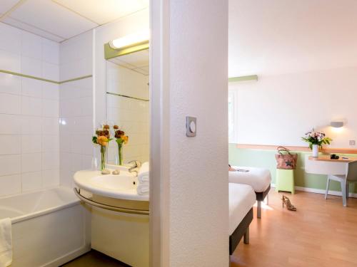 y baño con lavabo, bañera y espejo. en ibis budget Cannes Mougins en Mougins