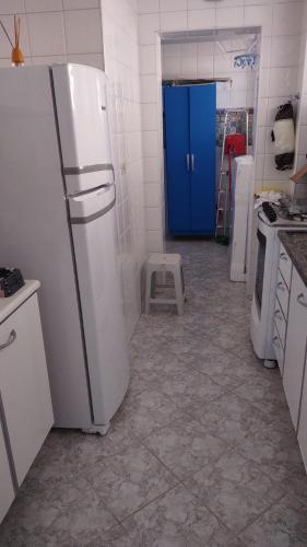 a kitchen with white appliances and a blue door at Apartamento 3 Dormitórios - Guarujá/SP - Lado Praia in Guarujá