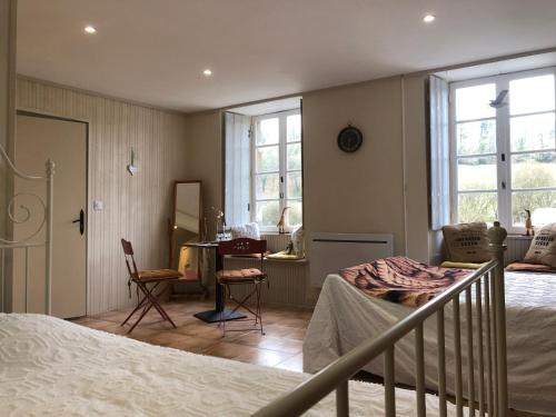 a bedroom with a bed and some chairs and windows at La Dernière Étape in Port-Launay