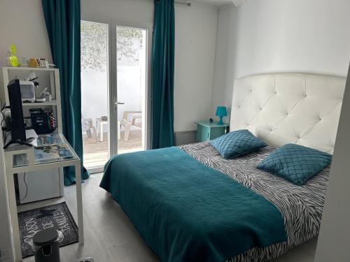 Schlafzimmer mit einem Bett mit blauer Bettwäsche und einem Fenster in der Unterkunft Chambres d'Hôtes Les Oliviers - Marignane in Marignane