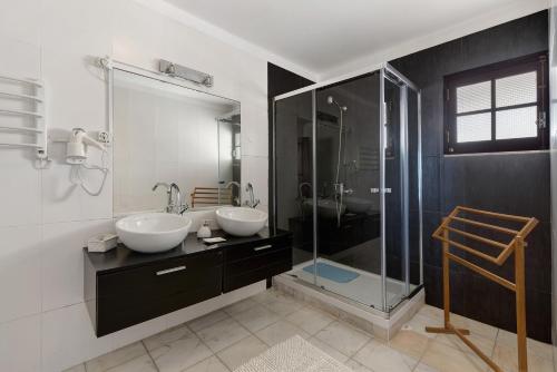 a bathroom with two sinks and a glass shower at Alto da Praia Villa in Colares