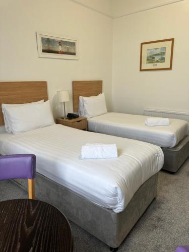 a hotel room with two beds and a chair at Exmouth Beach Hotel in Exmouth