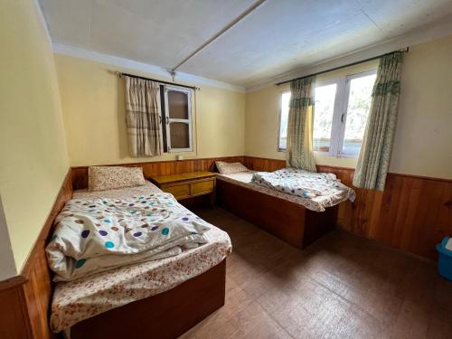 Habitación pequeña con 2 camas y ventana en Mount kailash lodge and resturant , Monjo en Monjo