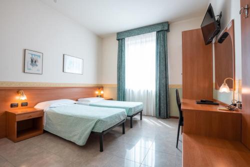 Habitación de hotel con 2 camas y escritorio en Hotel Stadio & Spa, en San Bonifacio