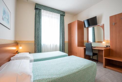 Pokój hotelowy z łóżkiem, biurkiem i oknem w obiekcie Hotel Stadio & Spa w mieście San Bonifacio