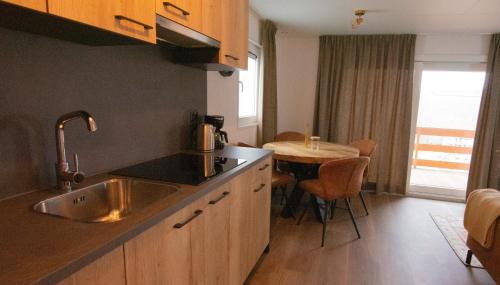 a kitchen with a sink and a table with chairs at Chalet Sjaantje in Egmond aan den Hoef