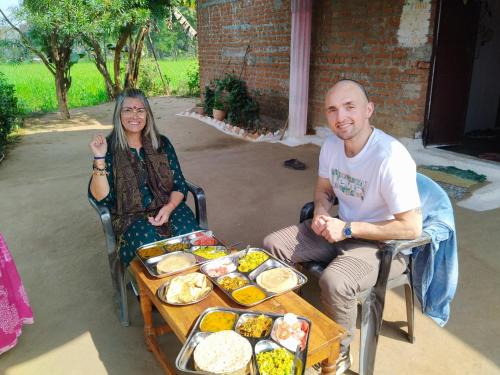 a man and a woman sitting next to a table of food at Maji Homestay Khajuraho in Khajurāho