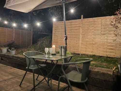 a patio table with two chairs and an umbrella at La bulle bien belge avec jacuzzi in Lasne