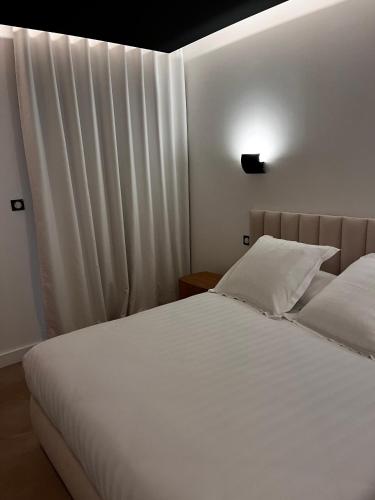 a bedroom with a bed with white sheets and a window at Villa Chiesa Maison Hôtelière in Le Grau-du-Roi