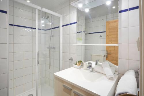 baño blanco con ducha y lavamanos en Hôtel Eliova Le Chaix, en L'Alpe-d'Huez