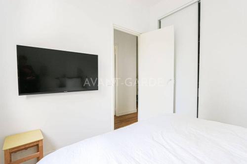 a bedroom with a white bed and a tv on a wall at Appartement 50m2 avec terrasse idéalement situé in Boulogne-Billancourt