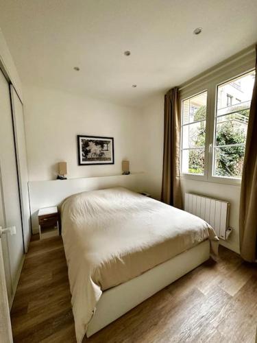 une chambre avec un grand lit et une fenêtre dans l'établissement Appartement 50m2 avec terrasse idéalement situé, à Boulogne-Billancourt