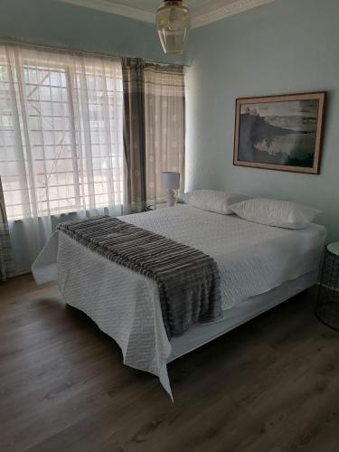 1 dormitorio con 1 cama con sábanas blancas y ventanas en SHANTI ANANDI en Klerksdorp