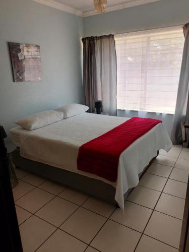 1 dormitorio con 1 cama grande con manta roja en SHANTI ANANDI en Klerksdorp