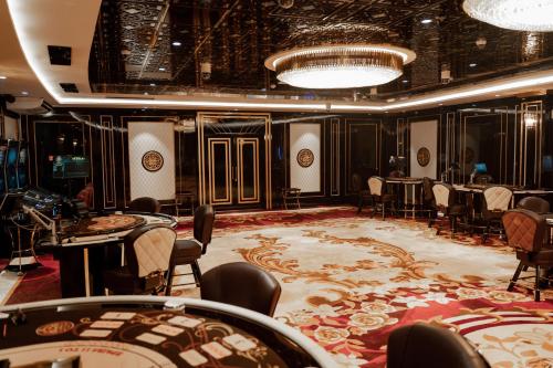 Grand Bellagio Batumi Convention & Casino Hotel في باتومي: غرفة طعام مع طاولات وكراسي وسجادة كبيرة