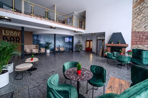a lobby with green chairs and tables and a fireplace at Kompleks Antałówka Termy & Med in Zakopane