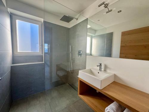 La salle de bains est pourvue d'un lavabo, d'une douche et d'un miroir. dans l'établissement Ferienwohnungen Preiss, à Schenna