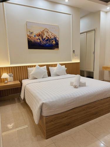 um quarto com uma cama grande e lençóis brancos em ELISA HOTEL em Pleiku
