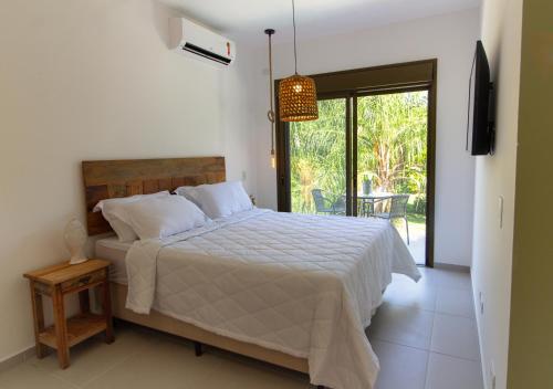 um quarto com uma cama com um edredão branco em Zaya Beach House em Ilhabela em Ilhabela
