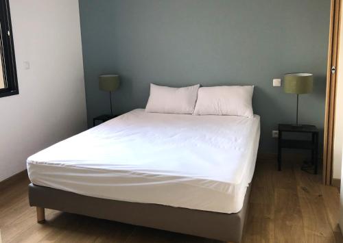 un lit avec des draps blancs et des oreillers dans une chambre dans l'établissement Mas GEORGES, à Saint Alban Auriolles