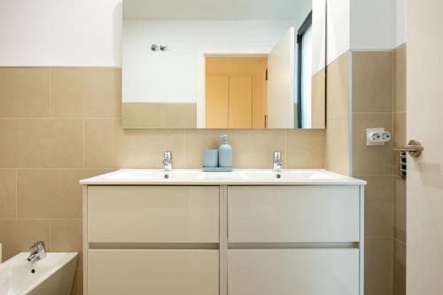 La salle de bains est pourvue d'un lavabo blanc et d'un miroir. dans l'établissement Charming 2 Bedroom Apartment by Torre Del Oro By Oui Sevilla, à Séville