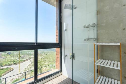 La salle de bains est pourvue d'une douche avec une porte en verre. dans l'établissement Luxury Stay at Bakish Peaks Villa with pool, 