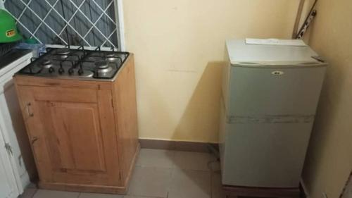 cocina pequeña con fogones y nevera pequeña en Julie-Appart, en Brazzaville