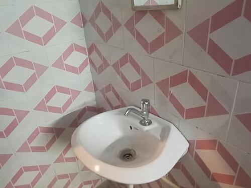 a white sink in a bathroom with pink and white tiles at Welcome paying guest house in Varanasi