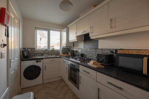 uma cozinha com armários brancos e um forno com placa de fogão em Pottery Wharf By Horizon Stays em Thornaby on Tees