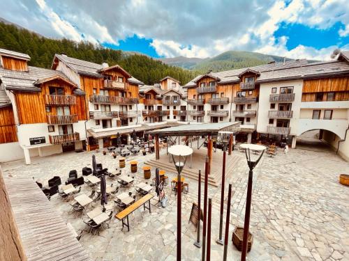 a group of buildings with tables and chairs in a courtyard at Les Orres 1800 - 6 places Plein Sud avec Piscine in Les Orres