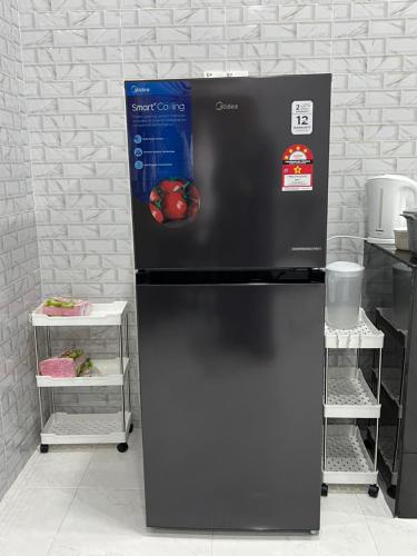 a black refrigerator with a picture of an apple on it at Homestay Singgah Tamu Al Amin in Bukit Payong