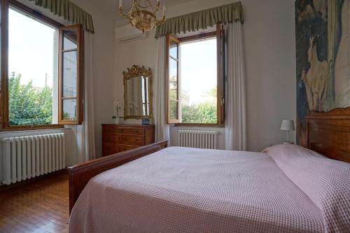 a bedroom with a large bed and two windows at Villa Lilli con piscina riscaldata in Montecatini Terme