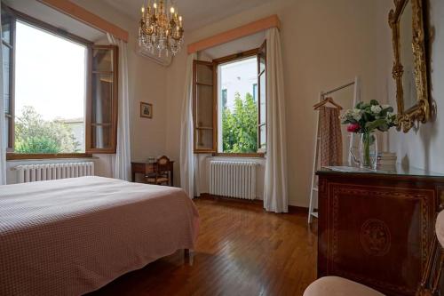 a bedroom with a bed and two windows at Villa Lilli con piscina riscaldata in Montecatini Terme