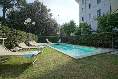 einen Pool mit zwei Liegen und Stühlen neben einem Gebäude in der Unterkunft Villa Lilli con piscina riscaldata in Montecatini Terme