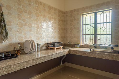 a kitchen with a counter with a window and a sink at Mulaqat Homestay in Siliguri