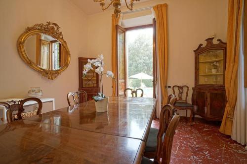 a dining room with a large wooden table and a mirror at Villa Lilli con piscina riscaldata in Montecatini Terme