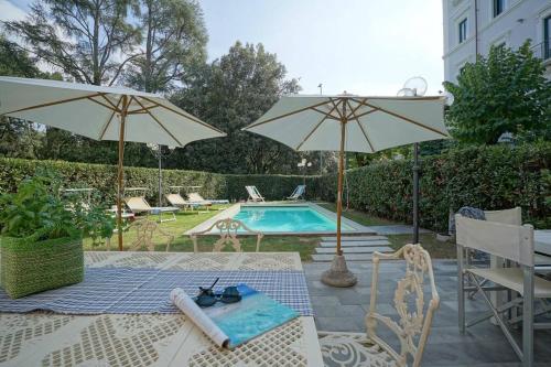 einen Pool mit 2 Sonnenschirmen sowie einem Tisch und Stühlen in der Unterkunft Villa Lilli con piscina riscaldata in Montecatini Terme