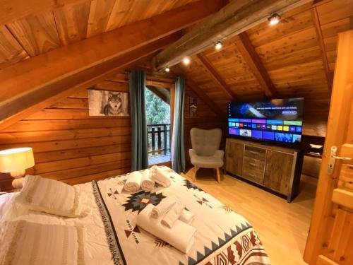 a bedroom with a bed and a flat screen tv at LE LOUP Chalet en bois in La Bresse