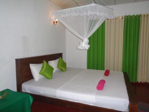 a bedroom with a bed with green and pink pillows at Green Valley Home stay in Talpe