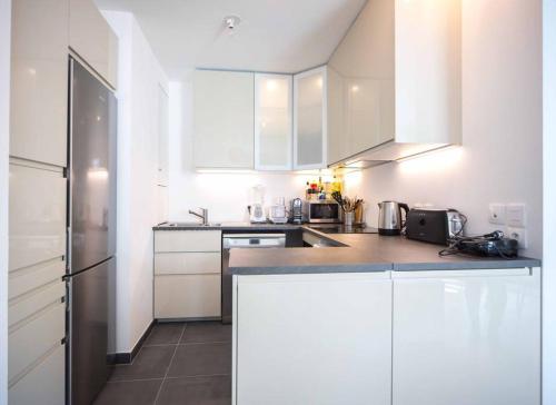 une cuisine avec des armoires blanches et un réfrigérateur en acier inoxydable dans l'établissement Paris comme on l'aime !, à Paris