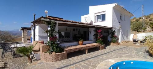 a white house with a bench in front of it at Bed & Breakfast Casa Ceratonia in Alora